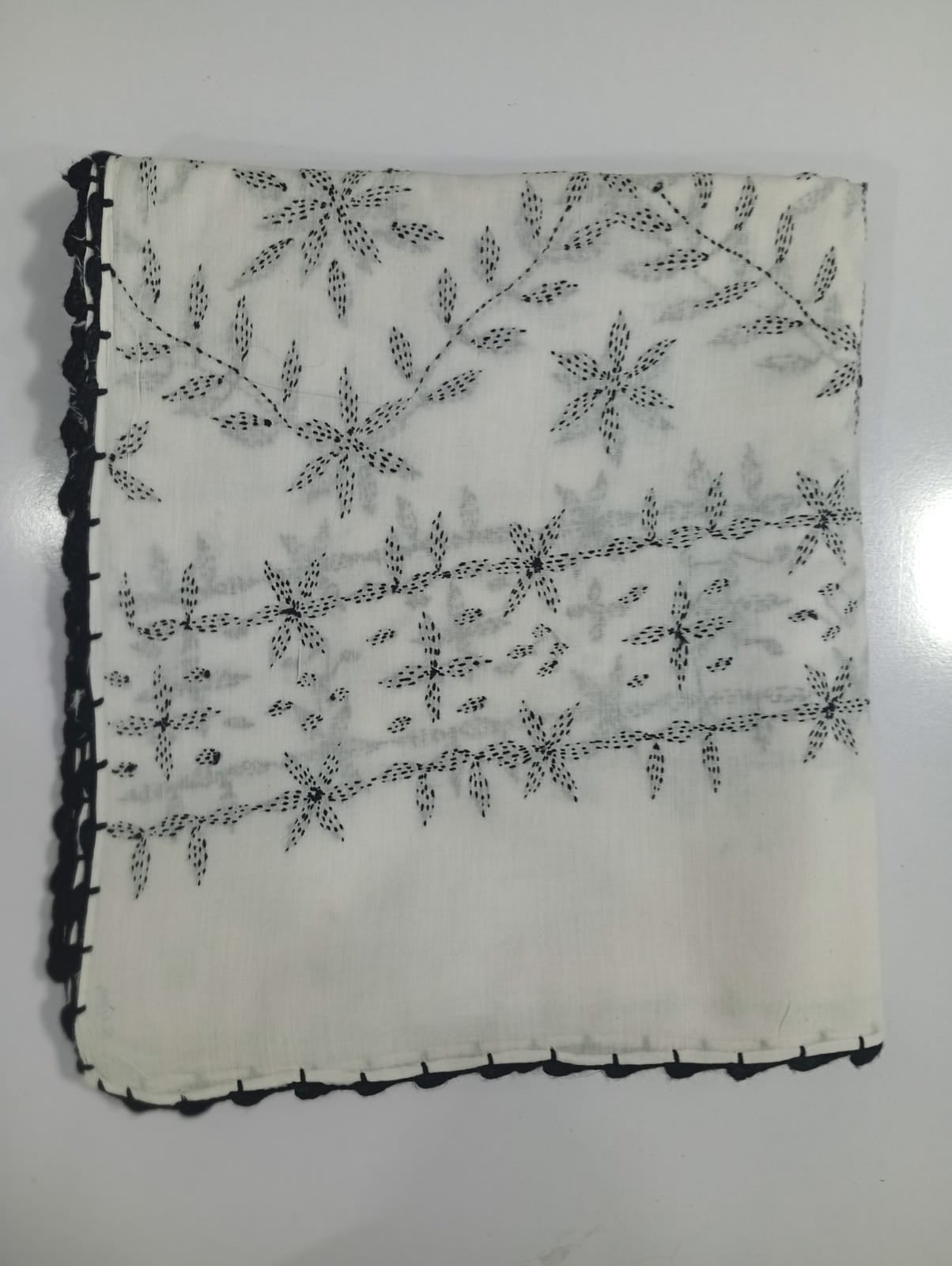 Decorative black thread embroidery on a white fabric with a plain background